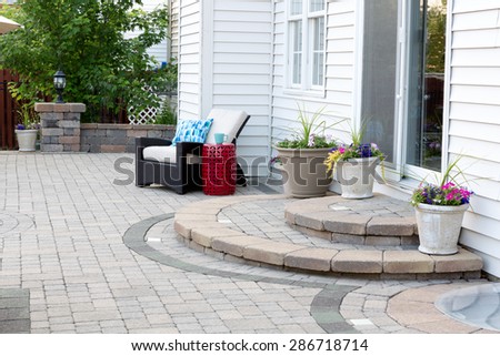 Rounded Steps to Back Door of Luxury Home, Stone Patio with Comfortable Wicker Furniture and Flower Pots