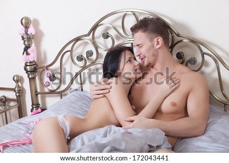 young couple in bed with sex toys.