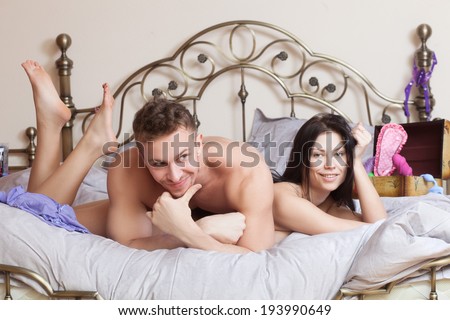 sexy couple lying in bed. use sex toys.