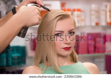 hairstylist makes hairstyle for beautiful girl