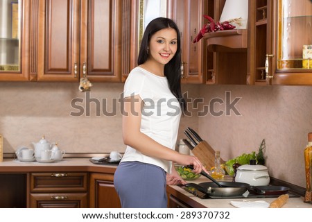 Kitchen Woman. Young beautiful girl holding a frying pan.  Kitchen background