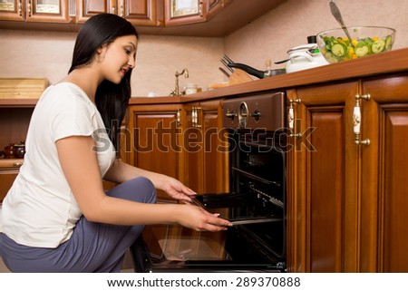 young woman checking how her cake is doing in the oven