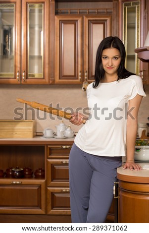 housewife holding a rolling pin. It stands in the kitchen