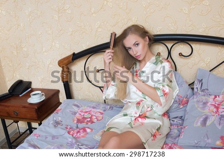 Sexy Young Girl Wearing White Nightdress Combing her Hair While Sitting on a Chair at her Room.