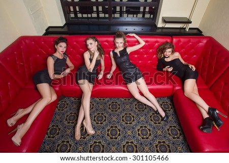 Four girl in black short dress on a red couch