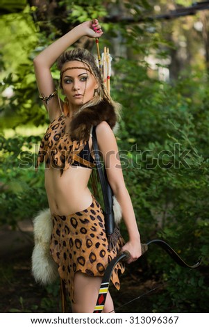 amazon woman posing with bow in green forest