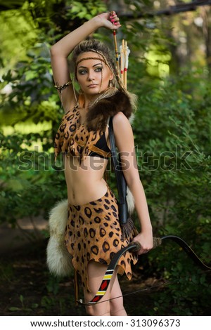 amazon woman posing with bow in green forest