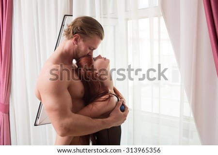 man and a woman in lingerie in a bedroom. standing by the curtains