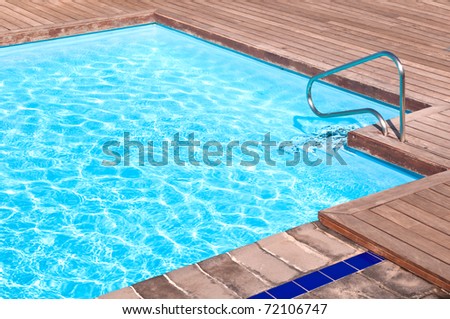 Wooden floor beside the blue swimming pool