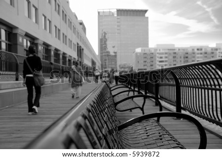 People leaving office in the afternoon - walking all in one direction, coming to one point. Focus on the bench. Shallow depth of field