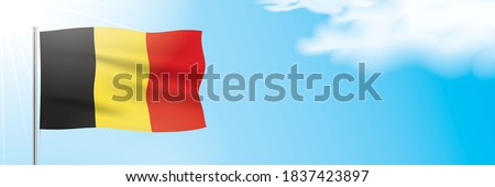 The official flag of Belgium waving on a blue sky background. Horizontal vector banner design with the Kingdom of Belgium flag hanging on a sunny background with white clouds and copy space.