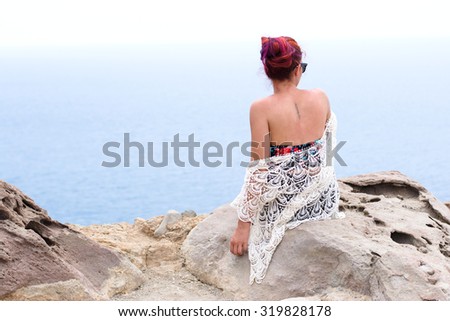 Beautiful woman on top of a cliff watching the ocean