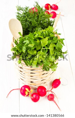 A bouquet of fresh different vegetables in a bowl wicker basket on white wooden background