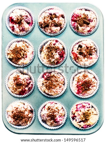 Raw muffin batter in muffin tin, isolated on white background, ready for baking. Closeup. Top view.