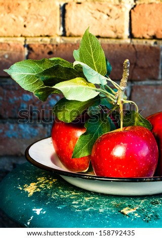 Red Big Apples with green leaves on rustic vintage background, close up. Still life photo with fresh picked red apples in a wooden background.