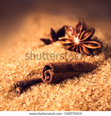 Cinnamon sticks and star anise on brown sugar on wooden background, christmas spices close up.