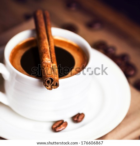 Coffee cup and coffee beans with cinnamon sticks on wooden  brown background, close up. Coffee  on a wood table macro.