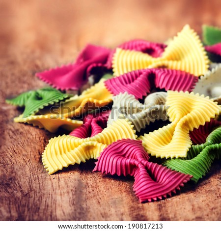 Fresh Italian Colourful Pasta on old wooden background close up.  Raw Bow tie  pasta macro. Italian Food.