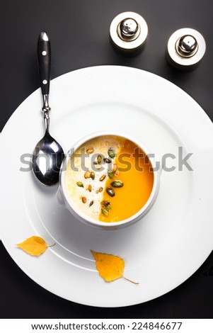 Pumpkin soup with cream and pumpkin seeds in a white bowl. Yellow Pumpkin soup made for Thanksgiving. Studio shot for restaurants