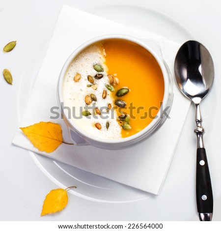 Pumpkin soup with cream and pumpkin seeds on a white plate macro. Yellow Pumpkin soup made for Thanksgiving. Studio shot for restaurants