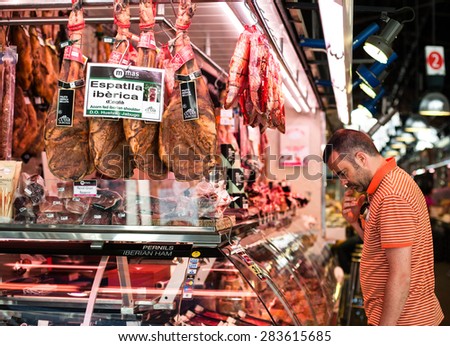 BARCELONA, SPAIN - MAY 12, 2015: Spanish Man looking at Meat shop with Iberian Ham at Bokeria Food Market