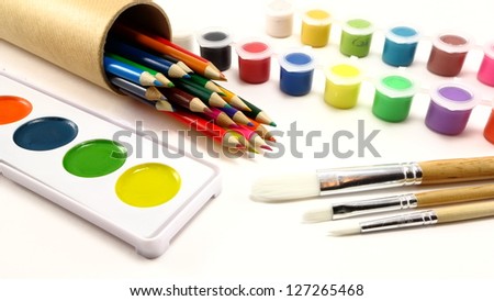 Colored pencils, paint brushes, and paint supplies on a white background