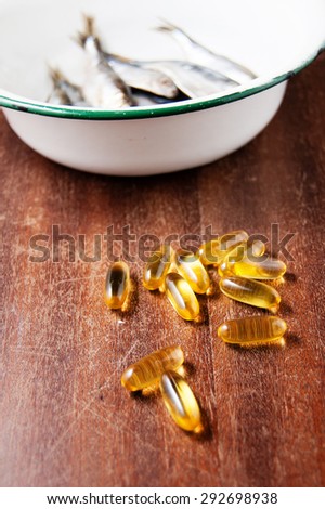 fish in white enamel bowl iron and vitamins omega three on a brown wooden table