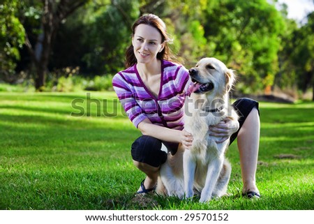Young woman and golden retriever sitting in the grass