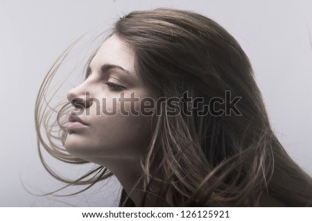 Face of beautiful young woman with hair flying in wind