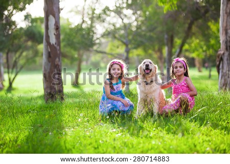 Two Beautiful little girls and their dog friend golden retriever in the park