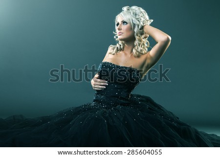 High fashion woman in sexy pose and  large formal dress sitting in studio