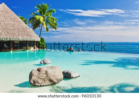 Infinity pool with palm tree overlooking tropical ocean