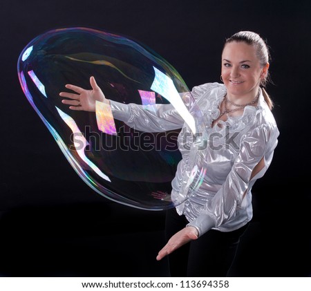 girl is doing soap bubble show on the black background
