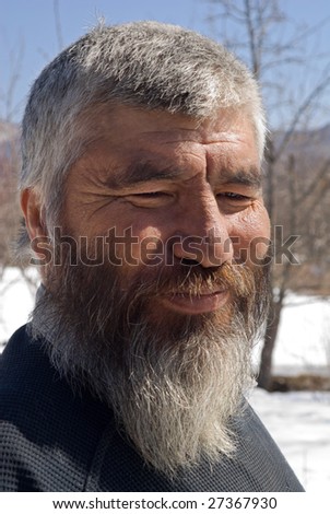 A portrait close up of the old smiling men with grey beard. Small indigenous people of Russian Far East.