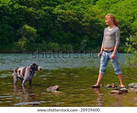 A young girl plays with dog at river.