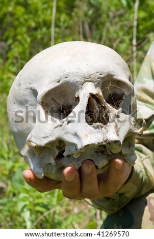 A close up of the human skull in hand of ranger. The skull of the unknown person has been found in a wood. Investigation is made.