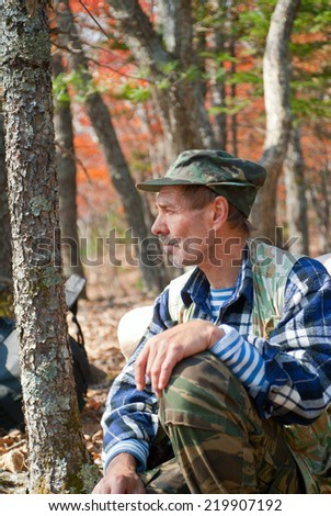 The man sits and relaxes in autumn forest.