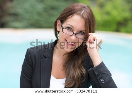 young pretty woman with glasses in business attire in front of a swimming pool