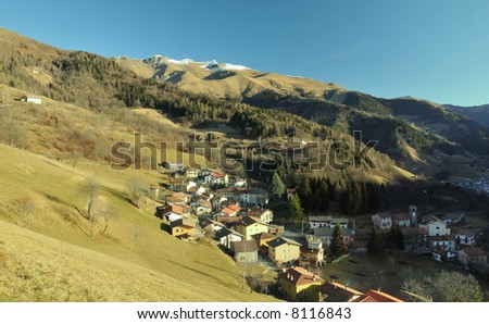 mountain village with snow capped mountains in background - far view