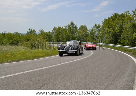 RADICOFANI (SI) ITALY - MAY 19: A red Maserati 150S overtakes a black Jaguar XK 120 during the 1000 Miglia 2012, on May 19, 2012 in Radicofani (SI)