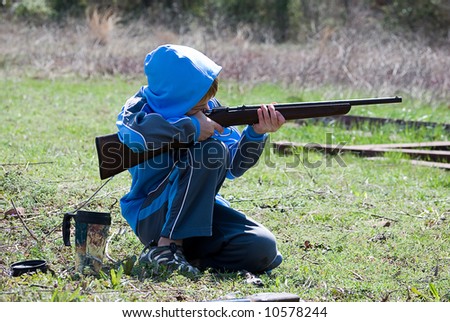 Boy kneeling while shooting rifle