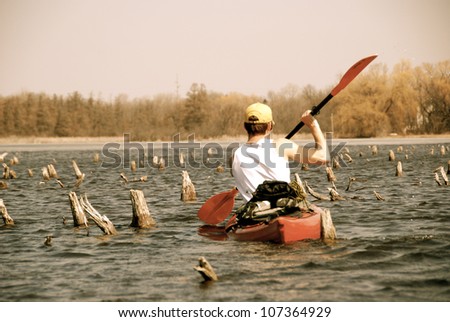 A man in a kayak paddles through stumpy lake