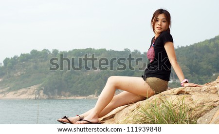 asian girl in the coastal with the sea and mountain background with innocent face and pose side view on Lamma Island in hong kong