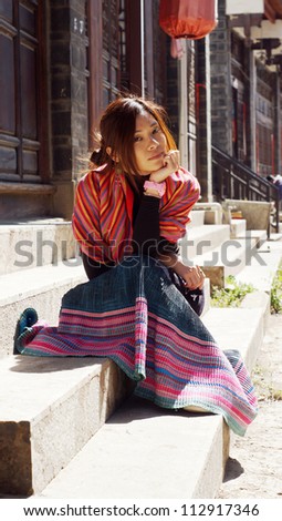 chinese girl  waiting someone ,with long skirt sit on the stair and thinking under the red lantern asian girl in Lijiang old town, Yunnan province, China