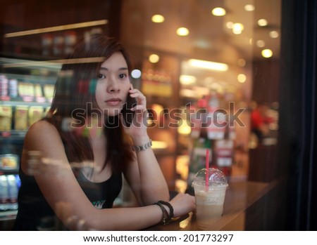 girl on call in cafe when someone late behind window , view from window