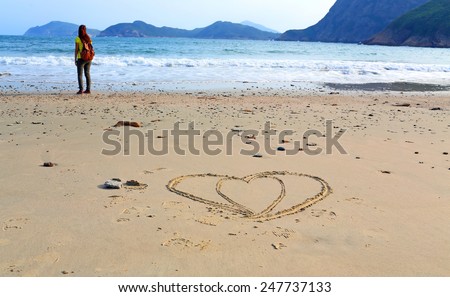 girl stand alone  after she draw two heart on the beach in valentine day