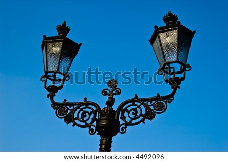 Wrought iron lamp post against blue sky