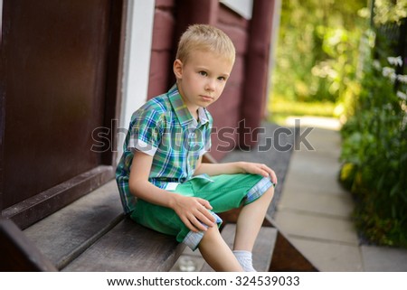 Smiling young blond boy sitting on porch steps at home ?