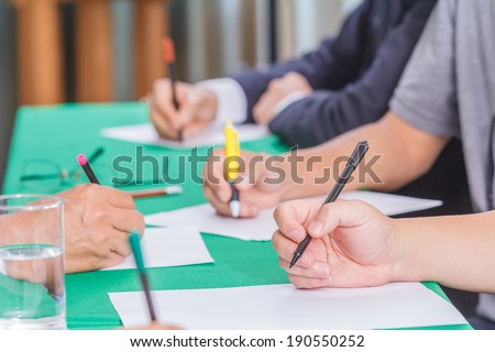 Businessmen hands is writing report about a meeting.