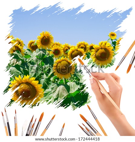 hand with paint brushes painting a beautiful summer landscape with sunflowers